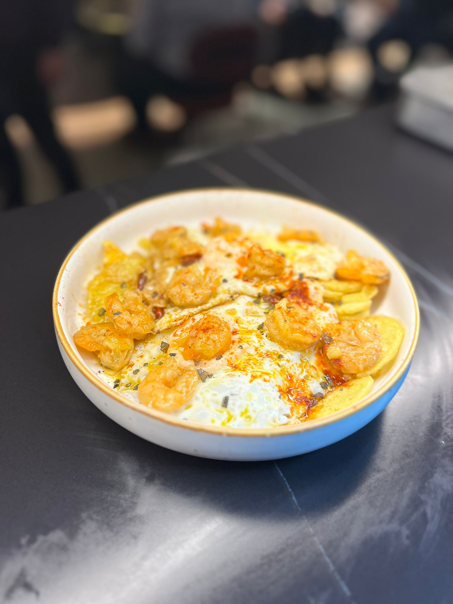 Huevos rotos con patatas y langostinos al ajillo